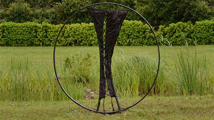 Sculpture « En roue libre », anneau de bronze avec drapé central, installée en plein champ.
